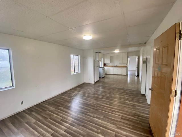 unfurnished living room with dark tile patterned flooring and a paneled ceiling