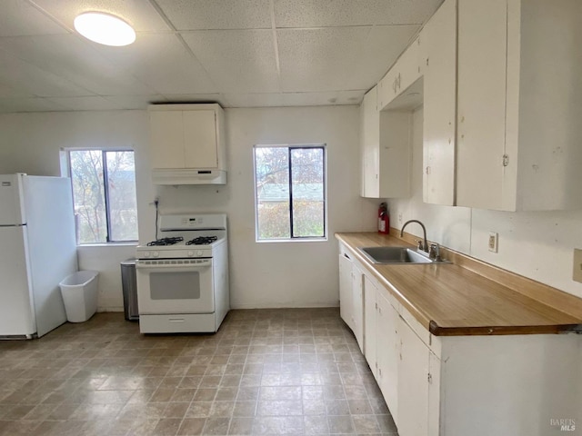 kitchen featuring white cabinets, white appliances, sink, a paneled ceiling, and light tile patterned floors