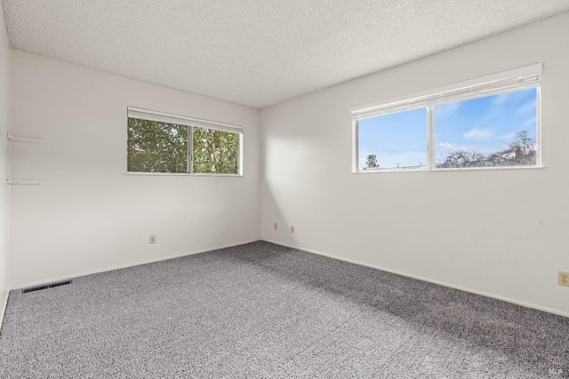 unfurnished room with baseboards, visible vents, carpet flooring, and a textured ceiling