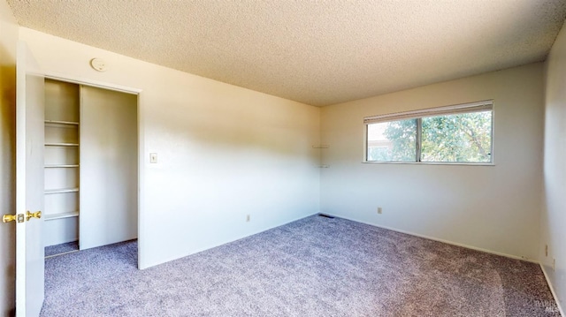 unfurnished room with carpet flooring and a textured ceiling