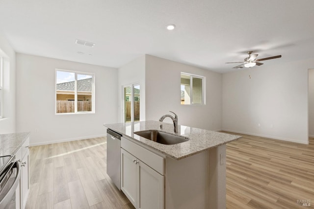 kitchen featuring light hardwood / wood-style flooring, stainless steel dishwasher, sink, a center island with sink, and stove