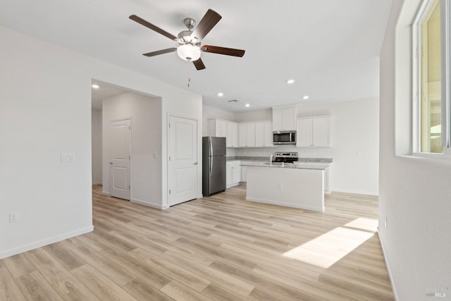 kitchen featuring a center island, appliances with stainless steel finishes, light hardwood / wood-style flooring, ceiling fan, and white cabinetry