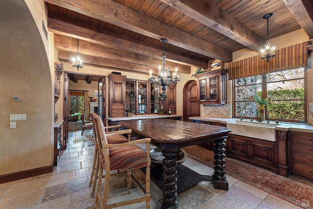 tiled dining room featuring wood ceiling, a notable chandelier, sink, and beam ceiling