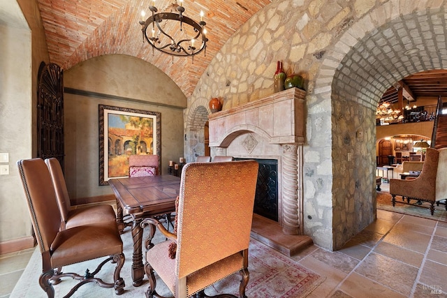 dining area featuring an inviting chandelier, tile flooring, vaulted ceiling, and brick ceiling