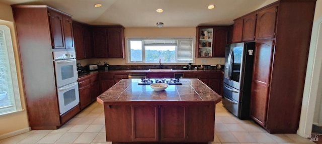 kitchen with light tile patterned flooring, stainless steel appliances, a kitchen island, and sink