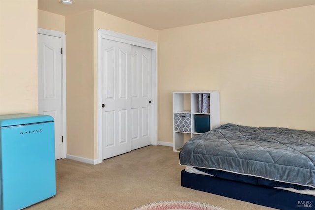 carpeted bedroom with a closet and refrigerator