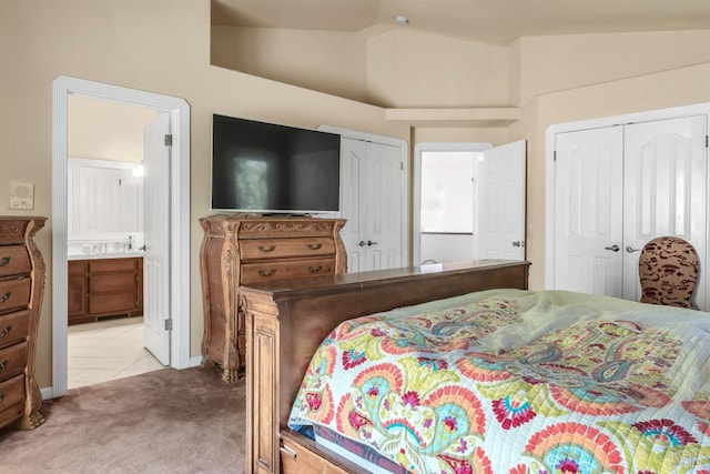 carpeted bedroom with ensuite bathroom and lofted ceiling