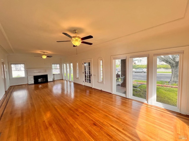 unfurnished living room featuring ceiling fan, a fireplace, and plenty of natural light