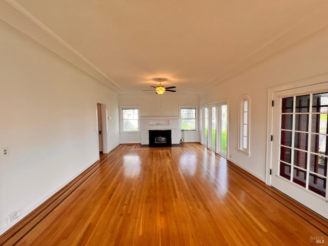 unfurnished living room with ceiling fan, a brick fireplace, and light hardwood / wood-style flooring