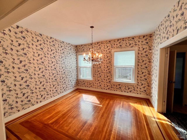 spare room with light hardwood / wood-style flooring and a chandelier