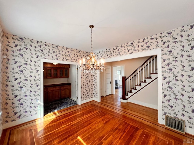 unfurnished room featuring a chandelier and dark hardwood / wood-style floors