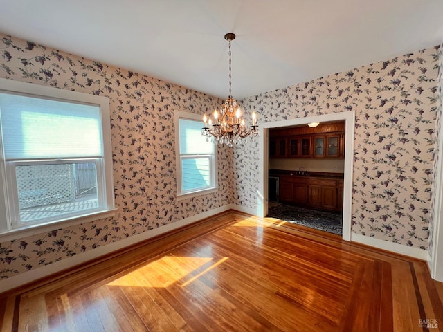 spare room with sink, hardwood / wood-style flooring, and an inviting chandelier