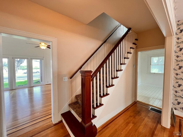 staircase with ceiling fan and light hardwood / wood-style flooring