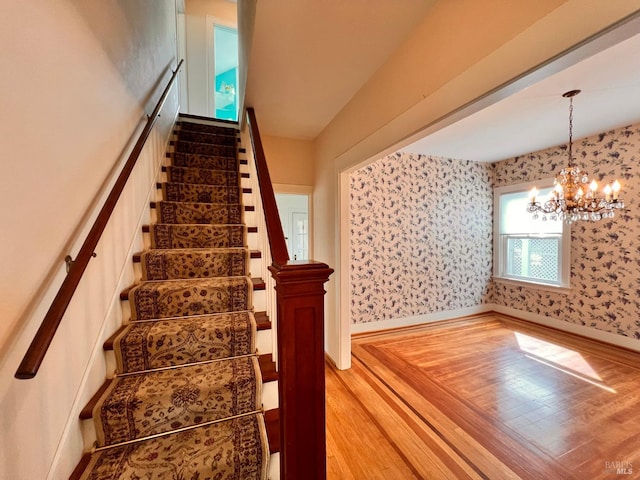 stairs with light wood-type flooring and a chandelier