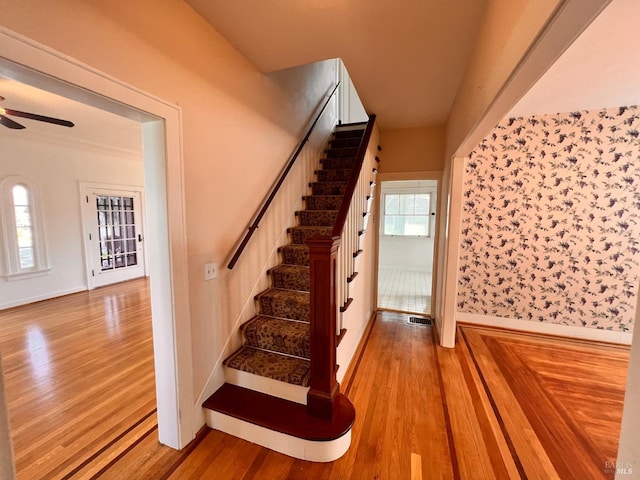 staircase with ceiling fan and light hardwood / wood-style flooring