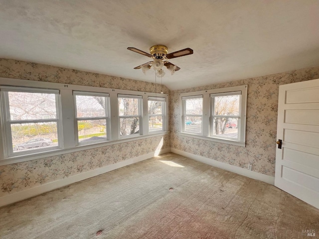 carpeted empty room with ceiling fan, lofted ceiling, and plenty of natural light