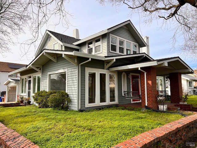 rear view of property featuring a yard and a porch