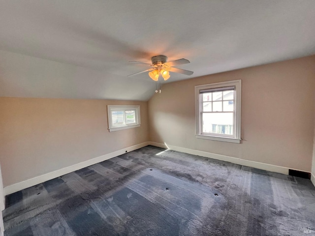 spare room featuring ceiling fan, dark carpet, and vaulted ceiling