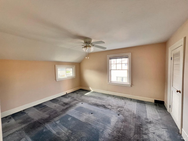 spare room featuring ceiling fan, vaulted ceiling, and dark colored carpet