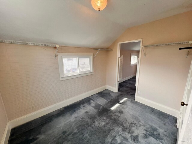 additional living space featuring dark carpet and vaulted ceiling