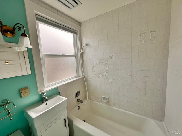 bathroom with vanity, tiled shower / bath combo, and a healthy amount of sunlight