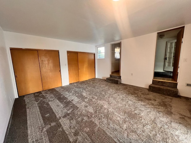 unfurnished bedroom featuring carpet floors and multiple closets