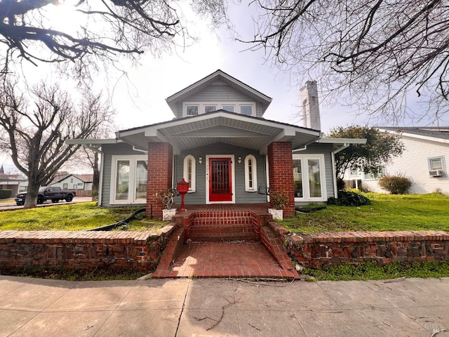 view of front of home with covered porch and a front lawn