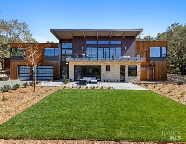 rear view of house with a lawn, a balcony, outdoor lounge area, and a patio