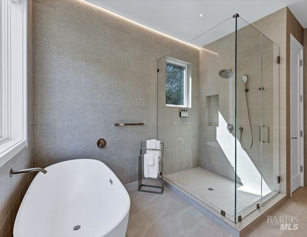 bathroom with shower with separate bathtub, tile walls, and tile flooring