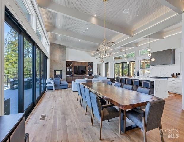 dining room featuring beamed ceiling, a high ceiling, an inviting chandelier, and light wood-type flooring