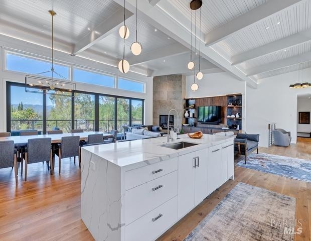 kitchen with white cabinets, plenty of natural light, light hardwood / wood-style flooring, pendant lighting, and a large fireplace