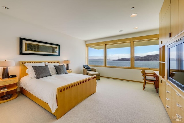 bedroom with a water view and light carpet