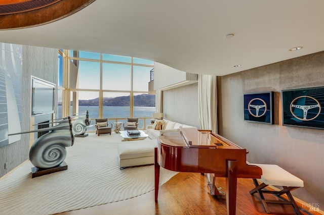 living room featuring a water and mountain view, hardwood / wood-style flooring, and a wall of windows