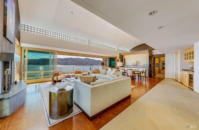 living room with a mountain view, lofted ceiling, beverage cooler, and hardwood / wood-style flooring