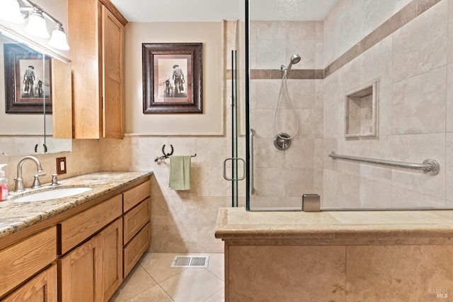 bathroom with an enclosed shower, tile patterned floors, vanity, and tile walls