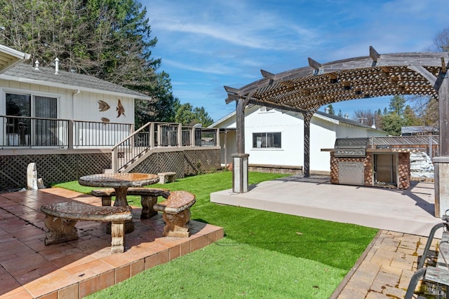 view of yard featuring an outdoor kitchen, a wooden deck, a pergola, and a patio