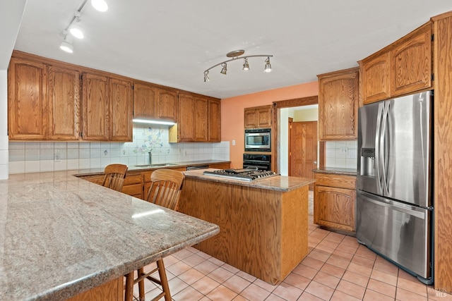 kitchen featuring a center island, a breakfast bar, sink, appliances with stainless steel finishes, and backsplash