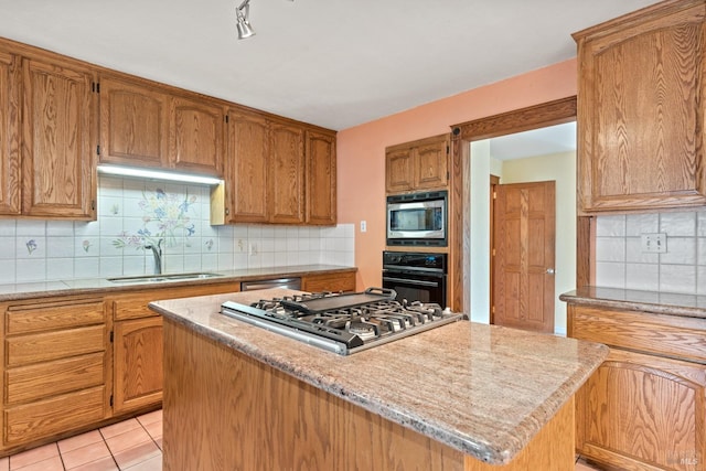 kitchen with stainless steel appliances, decorative backsplash, sink, and a center island