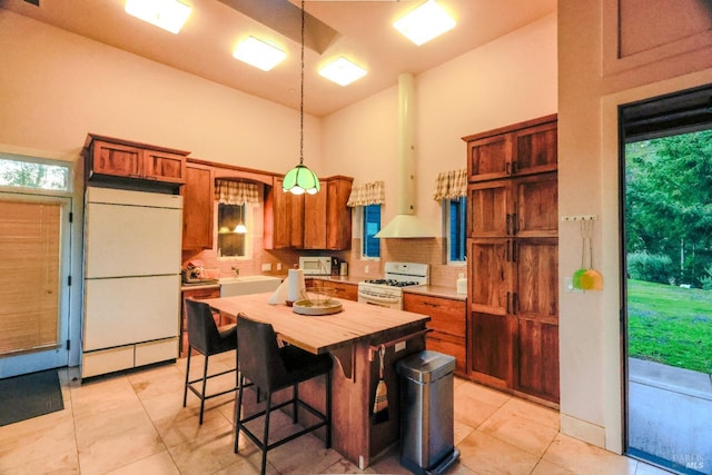 kitchen featuring light tile floors, refrigerator, decorative light fixtures, and white gas stove