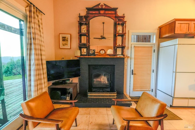 living room featuring ceiling fan, light tile floors, and a fireplace