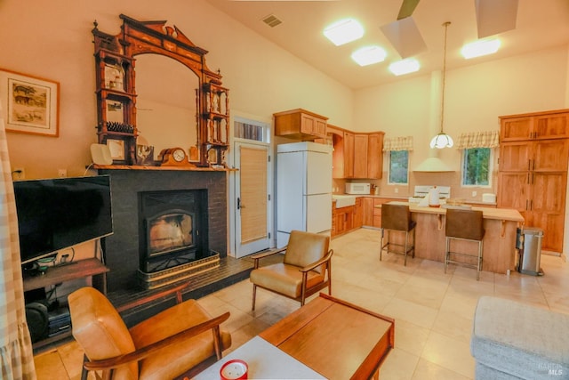 tiled living room featuring high vaulted ceiling and a brick fireplace