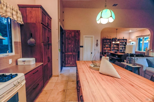 kitchen featuring light tile floors, decorative light fixtures, and wood counters