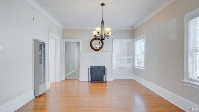 unfurnished living room with a chandelier, light hardwood / wood-style floors, and a brick fireplace