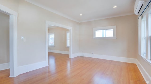 unfurnished room with an AC wall unit, light hardwood / wood-style floors, and a healthy amount of sunlight