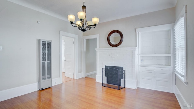 unfurnished living room featuring light hardwood / wood-style floors, a notable chandelier, and a fireplace