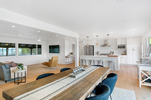 dining room with a healthy amount of sunlight, light hardwood / wood-style floors, ceiling fan, and sink