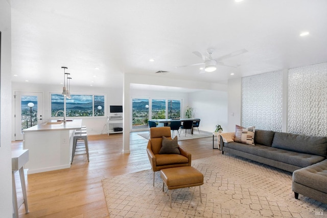 living room with light hardwood / wood-style flooring, ceiling fan, and sink