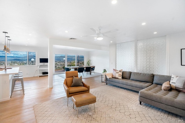 living room with light hardwood / wood-style floors and ceiling fan