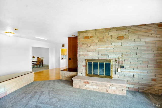 unfurnished living room featuring a stone fireplace and carpet floors