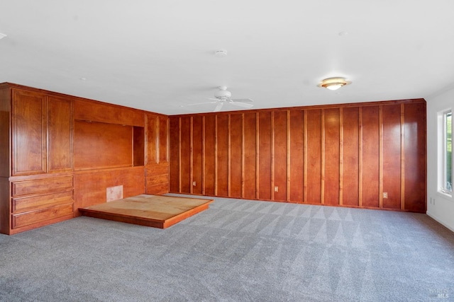 spare room featuring wooden walls, light carpet, and ceiling fan